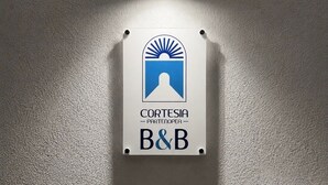 Un letrero montado en la pared con un logotipo y el texto 'CORTESIA PARTENORTE A&B'.