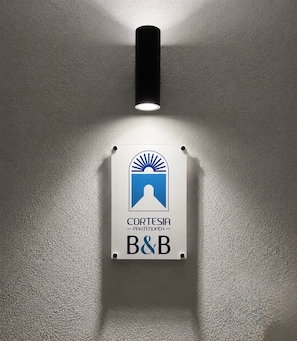 Un letrero montado en la pared con un logotipo y el texto 'CORTESIA PARTENORTE A&B'.