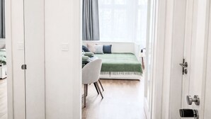 Ein Zimmer mit einem Bett, einem Schreibtisch und einem Stuhl, mit einem Fenster und Vorhängen.