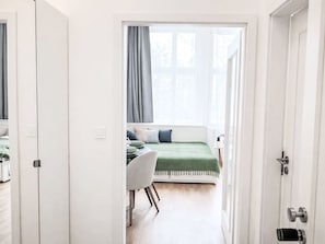 Ein Zimmer mit einem Bett, einem Schreibtisch und einem Stuhl, mit einem Fenster und Vorhängen.