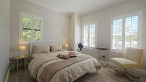 Een slaapkamer met een bed, bedlampen, een stoel en ramen.