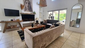 Ein modernes Wohnzimmer mit einer großen Couch, einem Flachbildfernseher, einem Kamin und einem großen Spiegel.