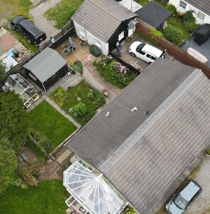 Een woonwijk met een huis, voorzien van een grote glazen kas, een verharde oprit en een auto op de oprit.