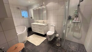 Une salle de bain moderne équipée d’une baignoire, de toilettes et d’une douche.