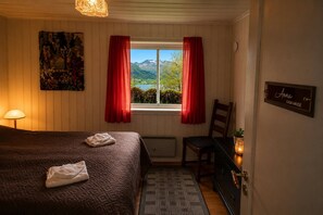 Une chambre à coucher avec un lit, une chaise, une fenêtre avec des rideaux, un tableau et un panneau accroché au mur.