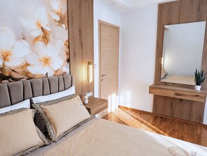 Ein Schlafzimmer mit Bett, Nachttisch, Kommode, Spiegel und einer Wand mit Blumenmuster.