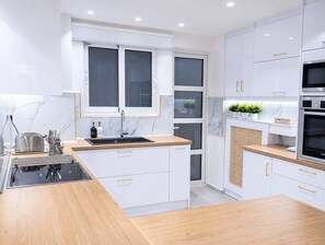Eine moderne Küche mit weißen Schränken, einer Holz Arbeitsplatte, einem Spülbecken und einem Backofen.