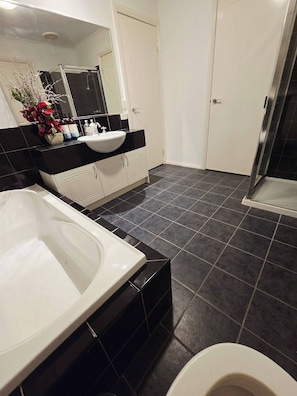 A bathroom with a bathtub, a sink, a mirror, and a shower area. - Panoramic view in Narre Warren North (Narre Warren North)