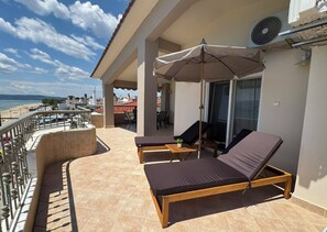 Ein Balkon mit zwei Liegestühlen, einem Tisch und einem Ventilator.