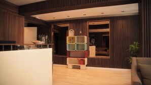 A modern living room with a wooden accent wall, a built-in bookshelf, and a large window. - Nevv City Hotel (İstanbul)