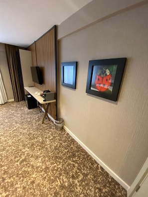 Habitación de hotel con escritorio, televisor y dos cuadros en la pared.