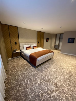 Una habitación de hotel con una cama, una mesita de noche, un armario y un espejo.