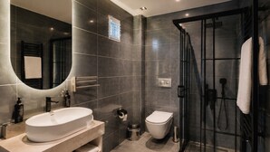 A modern bathroom with a large sink, toilet, and walk-in shower. - Nevv City Hotel (İstanbul)
