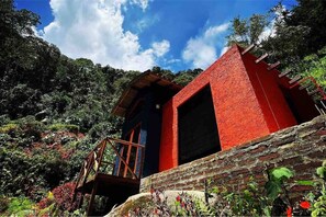 A red building with a wooden staircase leading to a door, surrounded by lush greenery. - Casa Montserrat - Like from a FAIRY TALE (Floridablanca)