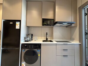Eine kompakte Küche mit Kühlschrank, Mikrowelle, Waschmaschine und Spüle.