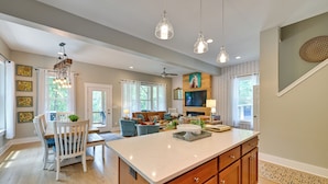 A spacious kitchen with a large island, wooden cabinets, pendant lighting, and a dining area with a white table and chairs. - Lakehouse Blue: Fire Pit, Hot Tub on Lake Norman! (Sherrills Ford)