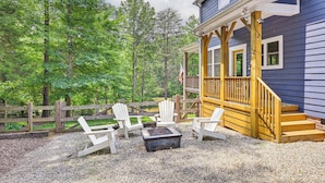 A wooden deck with Adirondack chairs and a fire pit, surrounded by a wooden fence and trees. - Lakehouse Blue: Fire Pit, Hot Tub on Lake Norman! (Sherrills Ford)