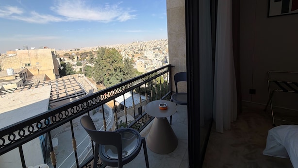 A balcony with a view of a cityscape, a round table, and two chairs. - 402 tara-JRE Jabal Al Lweibdeh with stunning view (Amman)