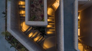 En modern arkitektonisk design med en spiraltrappa, betongkonstruktioner och integrerad grönska.