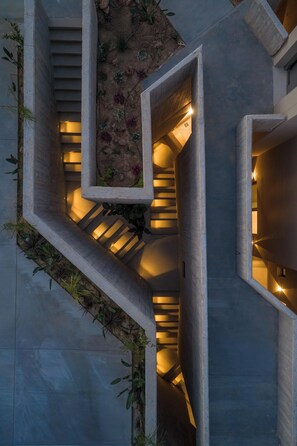 Ein modernes architektonisches Design mit Wendeltreppe, Betonstrukturen und integrierter Bepflanzung.