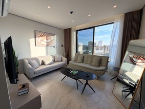 A modern living room with two sofas, a coffee table, a TV, and a large window with a city view. - 409 tara-JRE Jabal Al Lweibdeh with stunning view (Amman)