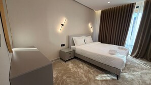 Een moderne hotelkamer met een groot bed, nachtkastjes en een wandlamp.