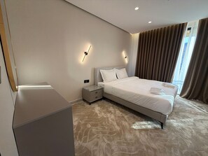 A modern hotel room with a large bed, bedside tables, and a wall-mounted light fixture. - 409 tara-JRE Jabal Al Lweibdeh with stunning view (Amman)
