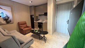 Ein gemütlicher Wohnraum mit Sofa, Sessel, Couchtisch, Waschmaschine und Küchenzeile.