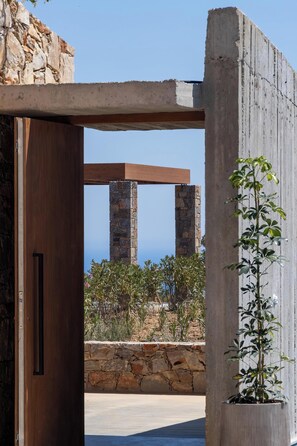 A doorway leading to a stone wall with a view of a mountainous landscape. - Carved From Calm by etouri (Heraklion)