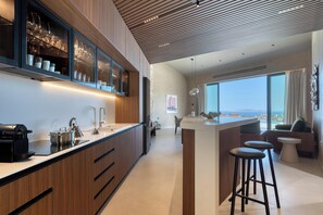A modern kitchen with a large island, wooden cabinetry, and a view of the city. - Carved From Calm by etouri (Heraklion)