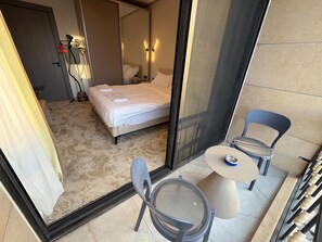 A hotel room with a bed, a small table with chairs, a mirror, and a door with a towel rack. - 410 tara-JRE Jabal Al Lweibdeh with stunning view (Amman)