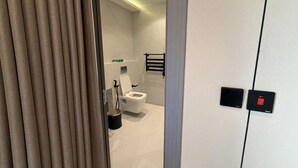 Un baño moderno con inodoro, secamanos y toallero.