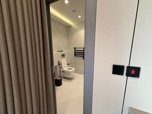 A modern bathroom with a toilet, a hand dryer, and a towel rack. - 410 tara-JRE Jabal Al Lweibdeh with stunning view (Amman)