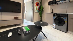 Una cocina moderna con lavadora, televisor de pantalla plana y comedor con mesa y sillas.