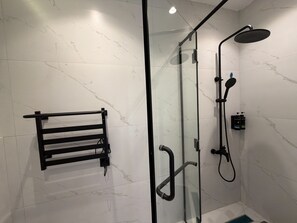 Um banheiro moderno com box de vidro, porta-toalhas preto e chuveiro manual.