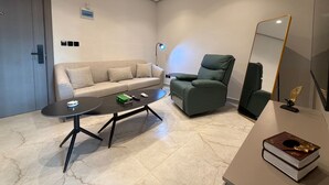 Una sala de estar moderna con un sofá, sillón, mesa de centro y un espejo grande.