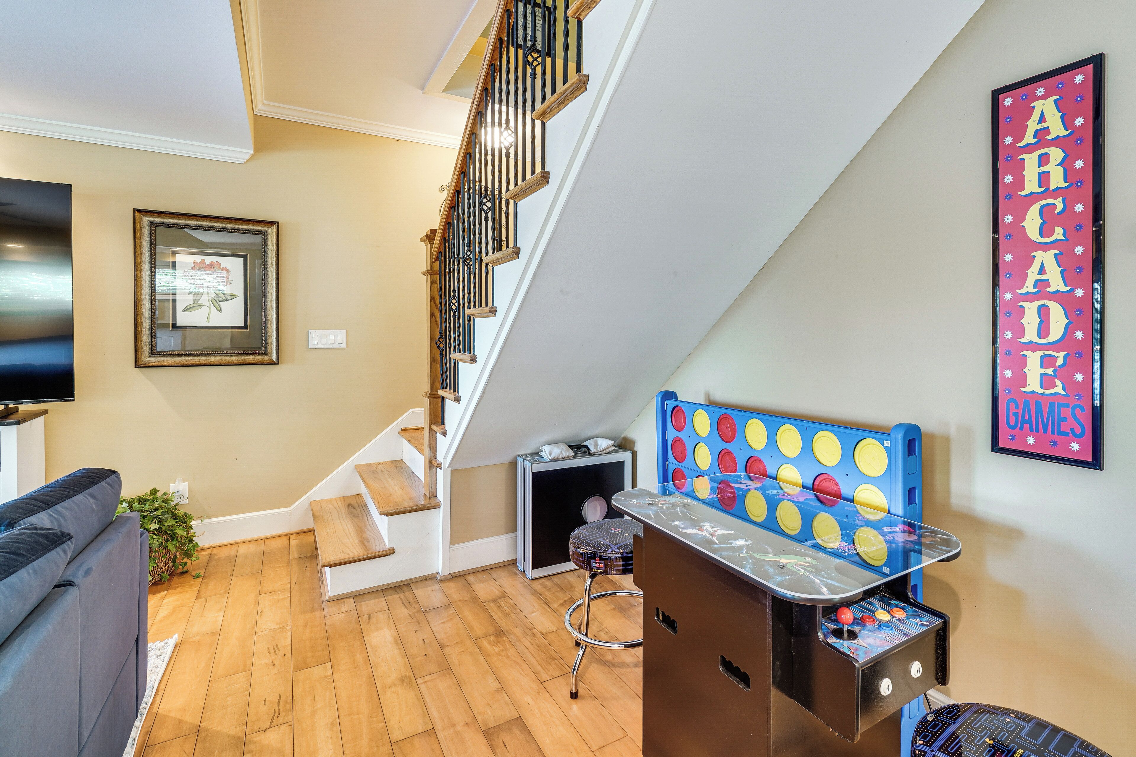 A living room with a staircase, a framed picture, a sofa, a small table, and a wall-mounted sign.