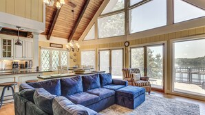 A spacious living area with a large sectional sofa, a kitchen with a bar, and large windows offering a view of the outdoors. - Decked Out! Private Dock Escape on Watts Bar Lake (Spring City)