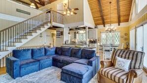 A spacious living area with a large sectional sofa, a striped armchair, and a staircase leading to an upper level. - Decked Out! Private Dock Escape on Watts Bar Lake (Spring City)