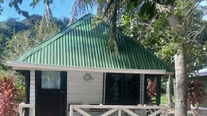 Un pequeño edificio con techo verde, paredes blancas y un porche de madera.