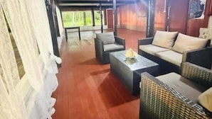 Un espacio de estar al aire libre con techo, mobiliario de mimbre, una mesa y vistas del exterior.