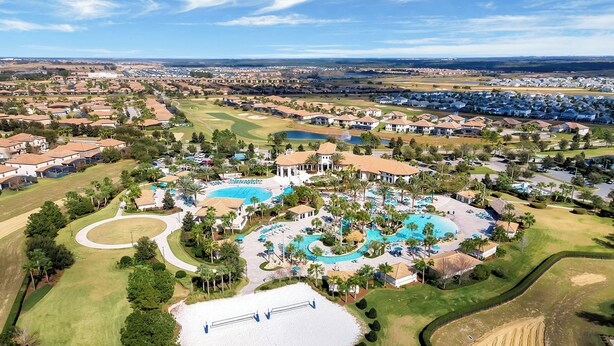 Vista aérea de una zona residencial con varias piscinas, campos de golf y una gran masa de agua.