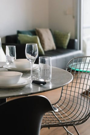 A dining table with plates, glasses, and cutlery, a chair, and a sofa in the background. - Modern Inner-City Stay in Valley|Heart of Brisbane (Fortitude Valley)