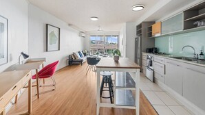 A modern kitchen with a dining area, a red chair, and a view of the city. - Modern Inner-City Stay in Valley|Heart of Brisbane (Fortitude Valley)