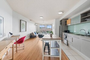 A modern kitchen with a dining area, a red chair, and a view of the city. - Modern Inner-City Stay in Valley|Heart of Brisbane (Fortitude Valley)