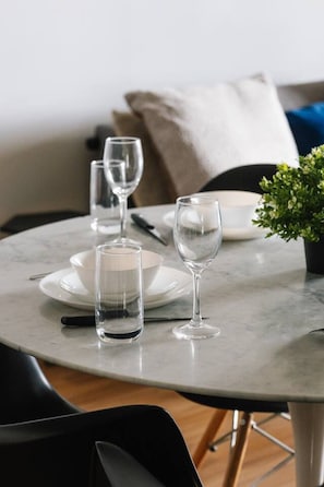 A round dining table with plates, glasses, and cutlery. - Modern Inner-City Stay in Valley|Heart of Brisbane (Fortitude Valley)