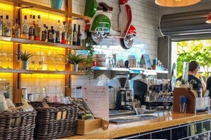 Eine Barbereich mit Regalen voller Flaschen, einer Kaffeemaschine und einem Tresen mit Körben.