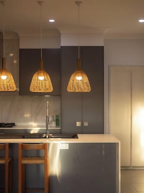 Una cocina moderna con luces colgantes, una isla central y un lavamanos empotrado.