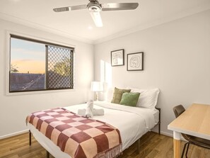 A hotel room with a bed, a desk, a window with a view, and a ceiling fan. - Stylish Family Home w/ A/C, 5 mins to Westfield (Upper Mount Gravatt)