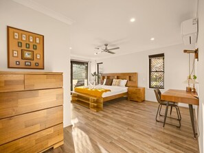 Un dormitorio con cama, cómoda de madera, escritorio y ventilador de techo.
